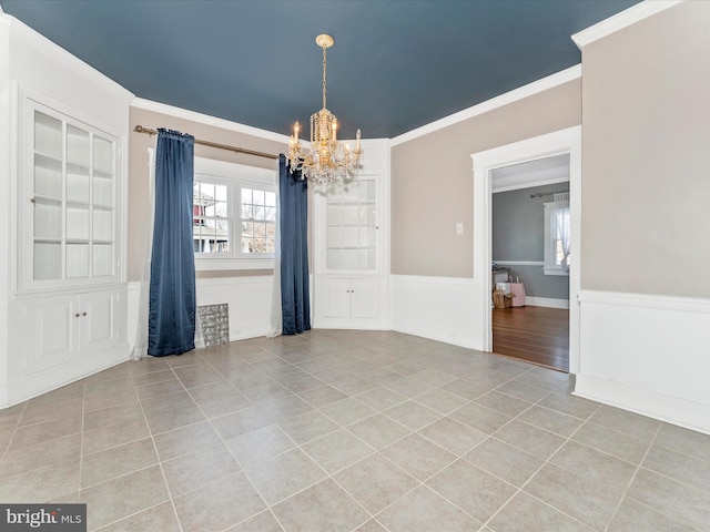 spare room featuring light tile patterned flooring, an inviting chandelier, and ornamental molding