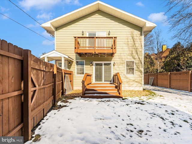 snow covered rear of property with a balcony