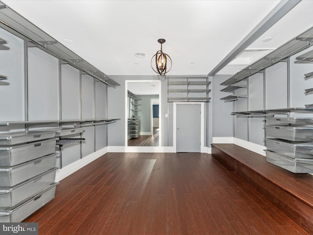 walk in closet featuring dark wood-type flooring and an inviting chandelier