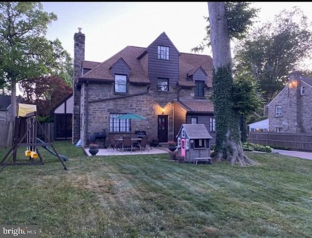 back of property with a patio area, a playground, and a lawn