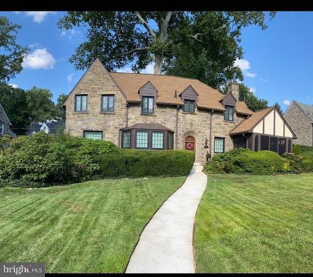 tudor-style house featuring a front yard