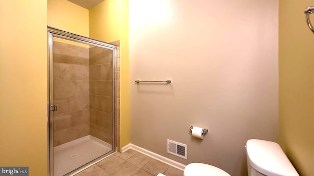 bathroom with toilet, tile patterned floors, and a shower with shower door