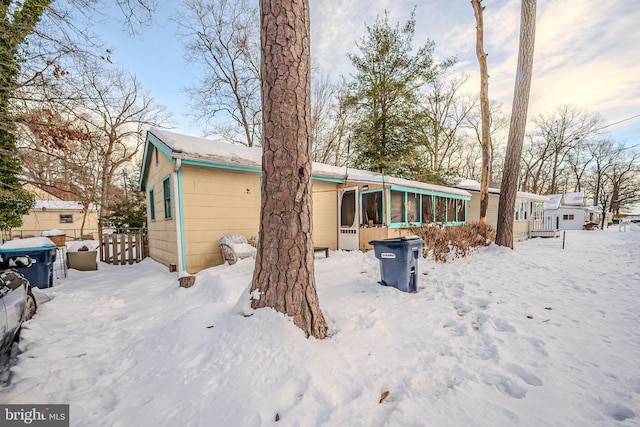 snow covered back of property with a sunroom