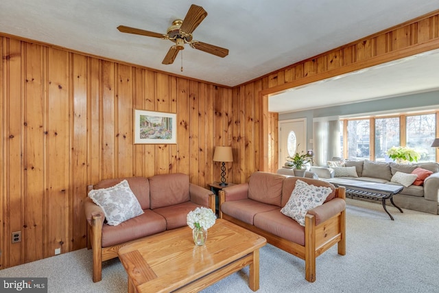 living room with carpet floors, ceiling fan, and wood walls