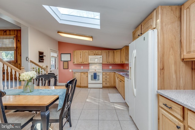 kitchen with light tile patterned floors, white appliances, light brown cabinets, and vaulted ceiling with skylight