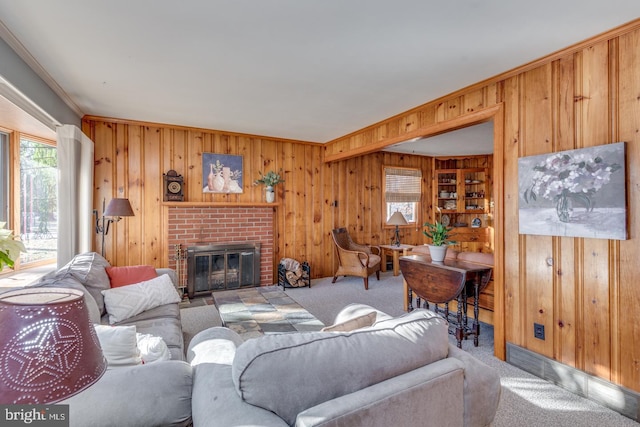 carpeted living room with crown molding, a fireplace, and wooden walls