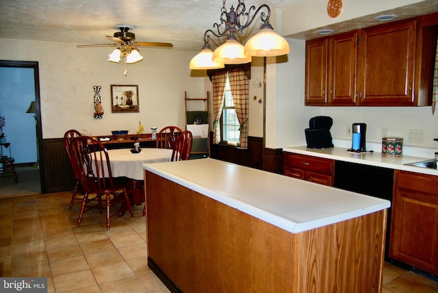 kitchen with ceiling fan with notable chandelier, pendant lighting, wooden walls, a center island, and light tile patterned floors