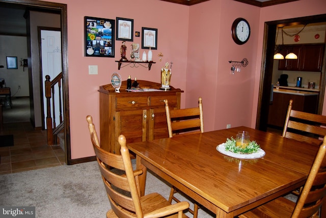 dining area with crown molding and light colored carpet