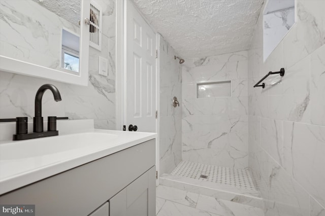 bathroom with a tile shower, tile walls, vanity, and a textured ceiling