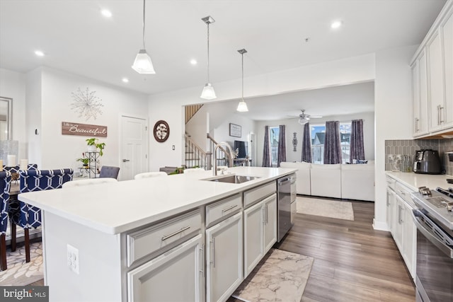 kitchen with a kitchen island with sink, sink, tasteful backsplash, white cabinetry, and stainless steel appliances