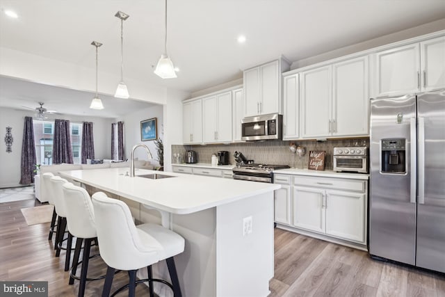 kitchen with a center island with sink, appliances with stainless steel finishes, white cabinets, and sink