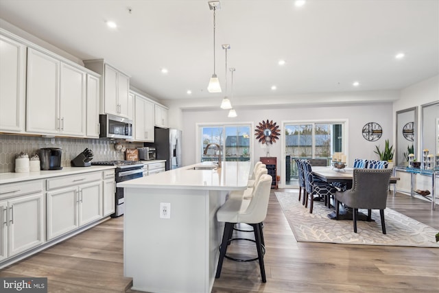 kitchen featuring decorative backsplash, pendant lighting, an island with sink, and stainless steel appliances