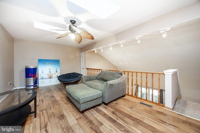 sitting room featuring ceiling fan, wood-type flooring, and lofted ceiling with skylight