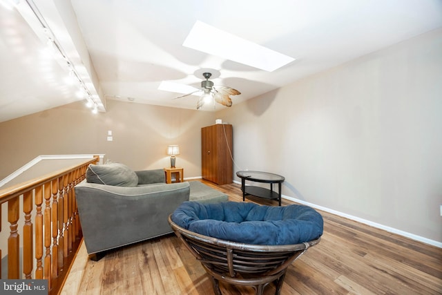 sitting room with hardwood / wood-style flooring, ceiling fan, lofted ceiling with skylight, and rail lighting