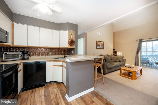 kitchen featuring black appliances, white cabinetry, kitchen peninsula, and sink