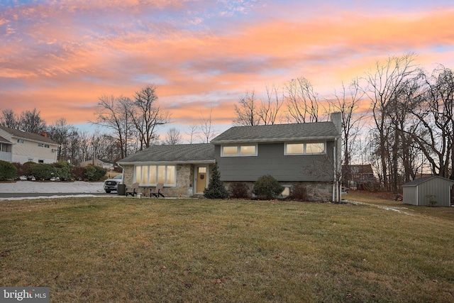 split level home with a storage shed and a lawn