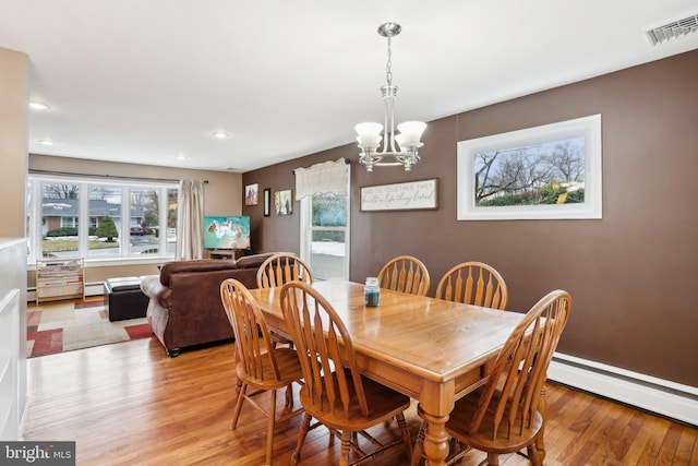 dining room featuring a chandelier, a baseboard radiator, and light hardwood / wood-style flooring