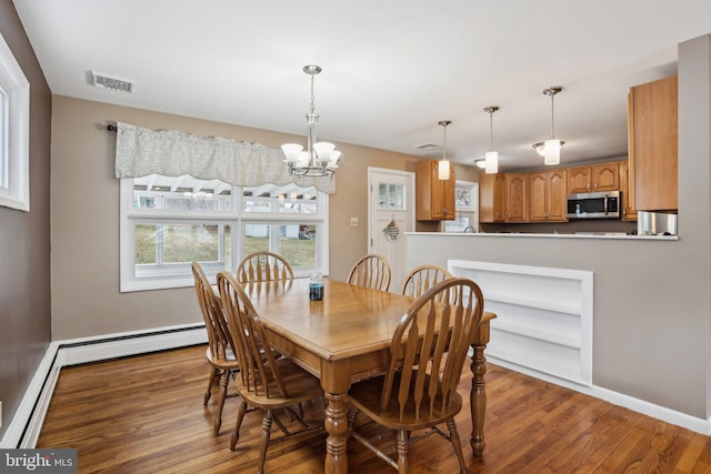 dining area featuring wood-type flooring, an inviting chandelier, and baseboard heating