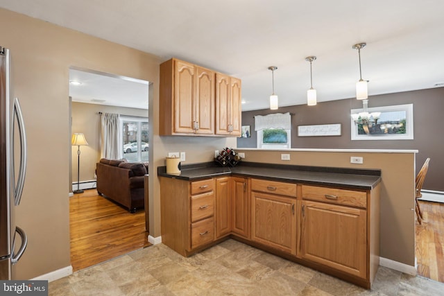 kitchen with baseboard heating, stainless steel refrigerator, plenty of natural light, and hanging light fixtures