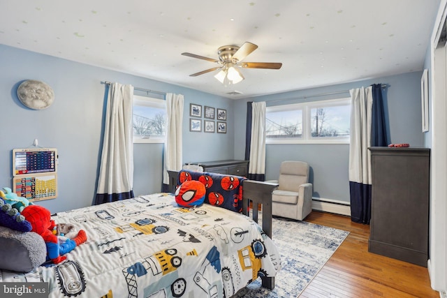 bedroom featuring ceiling fan, light wood-type flooring, and baseboard heating