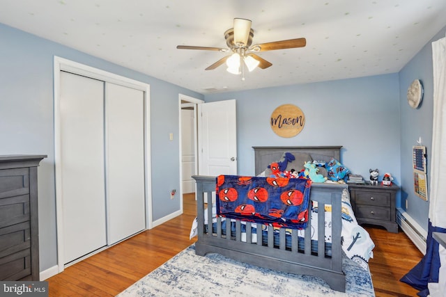 bedroom featuring ceiling fan, a closet, a baseboard radiator, and hardwood / wood-style flooring