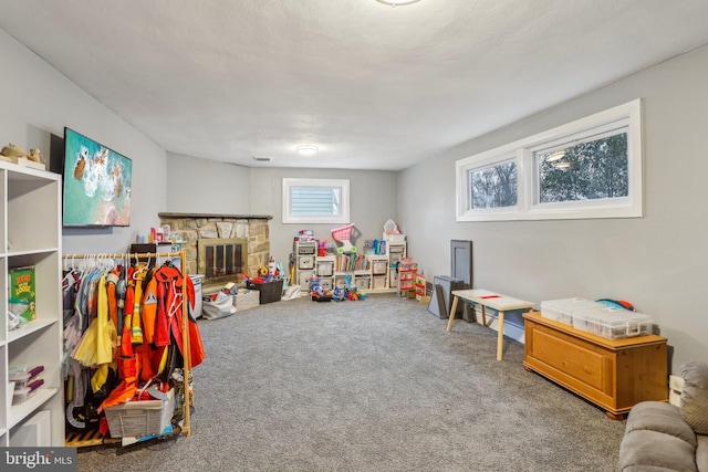 recreation room with a stone fireplace and carpet floors