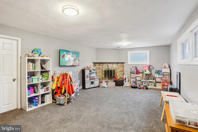 recreation room featuring carpet flooring, a fireplace, and a textured ceiling