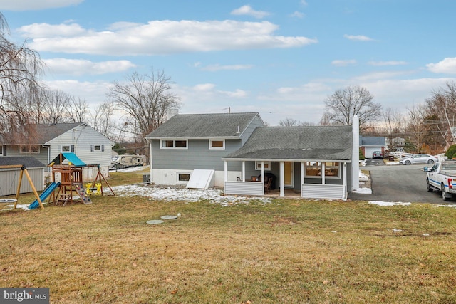 back of house with a lawn and a playground