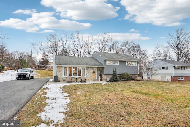 tri-level home featuring covered porch and a front yard