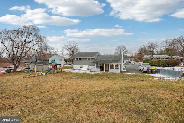 back of house with a playground and a lawn