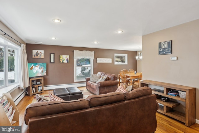 living room with a wealth of natural light, light wood-type flooring, and baseboard heating