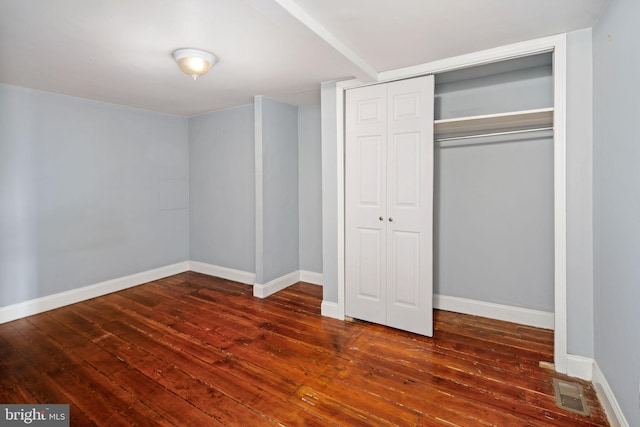 unfurnished bedroom featuring a closet and dark hardwood / wood-style floors