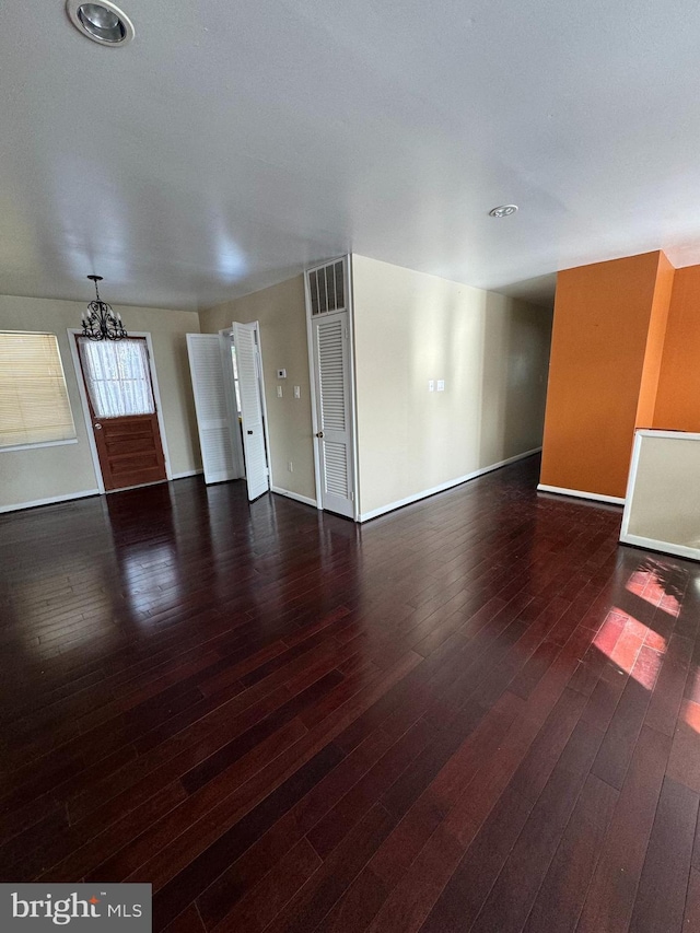 unfurnished living room featuring dark hardwood / wood-style floors and an inviting chandelier