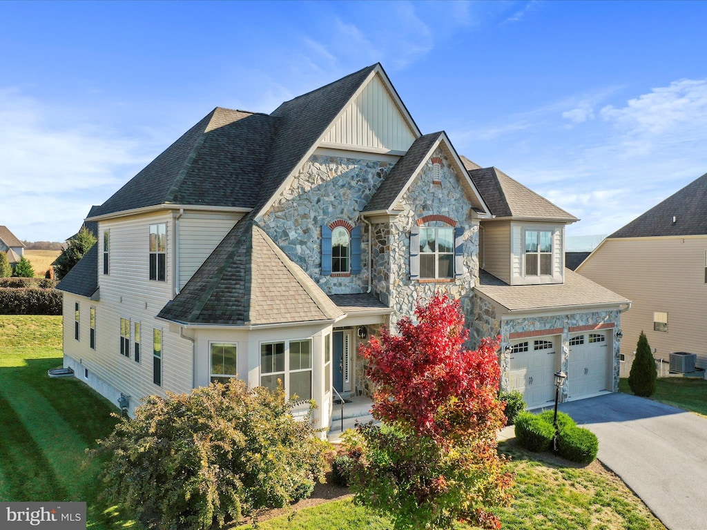 view of front of property with a front lawn, a garage, and central AC