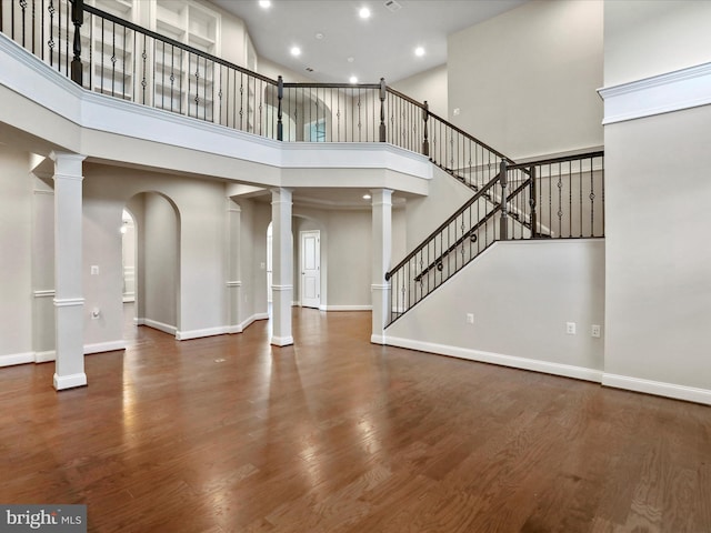 unfurnished living room featuring a towering ceiling and dark wood-type flooring