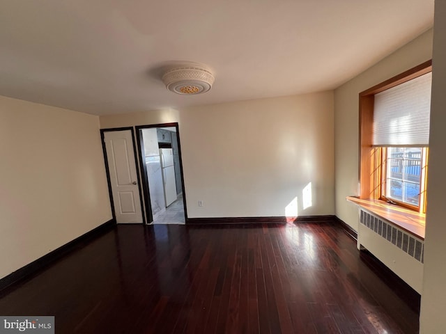 spare room featuring radiator and dark wood-type flooring