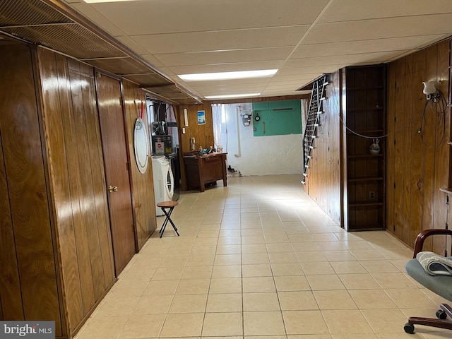 hall featuring a paneled ceiling, independent washer and dryer, and wooden walls