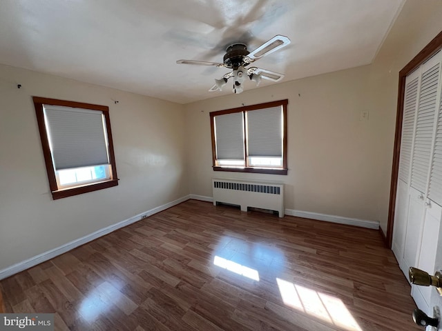 unfurnished bedroom featuring radiator, ceiling fan, a closet, and light wood-type flooring