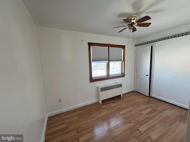 unfurnished bedroom featuring radiator heating unit, light hardwood / wood-style floors, and ceiling fan