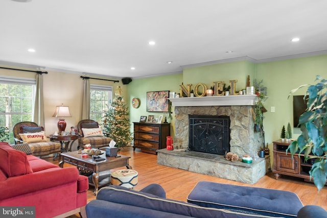 living room featuring a stone fireplace, crown molding, and hardwood / wood-style floors