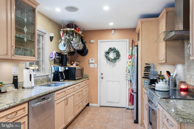 kitchen featuring appliances with stainless steel finishes, light stone counters, sink, wall chimney range hood, and light tile patterned flooring