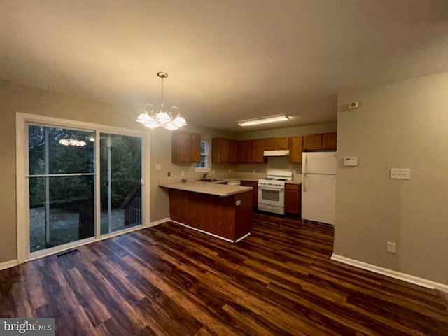 kitchen featuring kitchen peninsula, dark hardwood / wood-style floors, a notable chandelier, white appliances, and hanging light fixtures