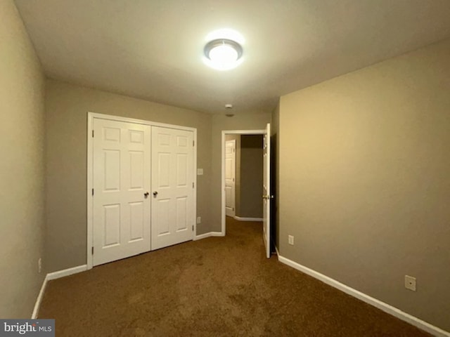 unfurnished bedroom with a closet and dark colored carpet