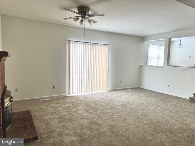 unfurnished living room featuring ceiling fan, a fireplace, and dark carpet