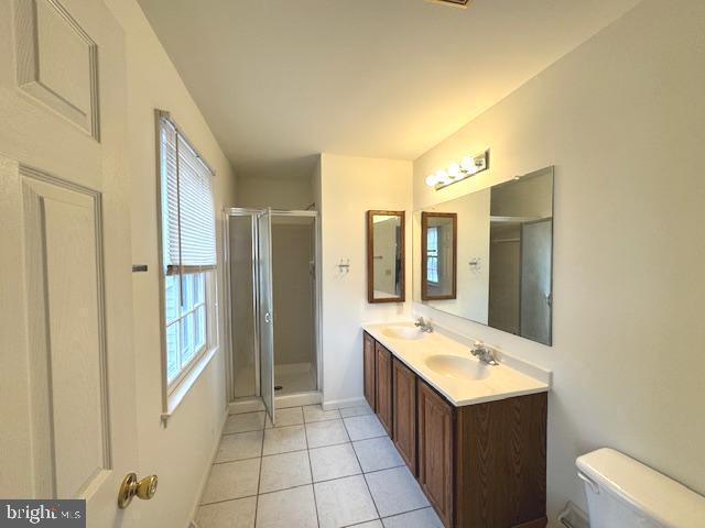 bathroom featuring toilet, a shower with shower door, tile patterned floors, and vanity