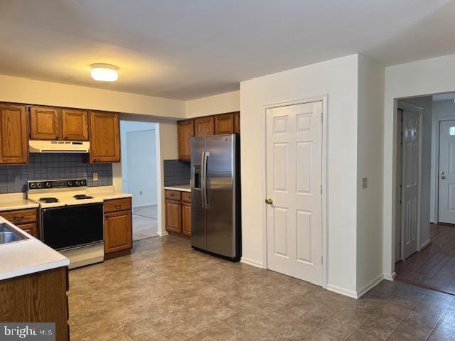 kitchen with sink, stainless steel fridge, electric stove, and decorative backsplash