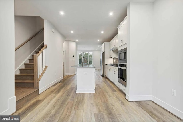 kitchen with sink, light hardwood / wood-style flooring, a kitchen island, white cabinetry, and stainless steel appliances