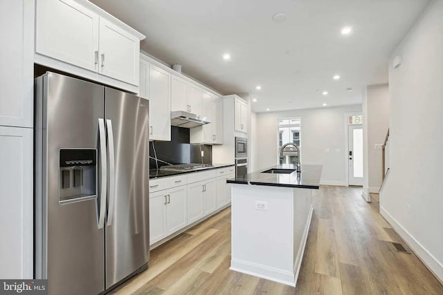 kitchen featuring stainless steel appliances, white cabinetry, a kitchen island with sink, and sink