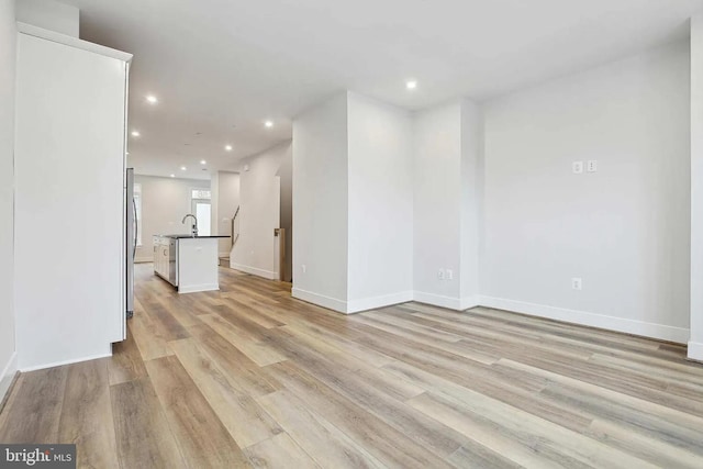 unfurnished living room with light wood-type flooring and sink