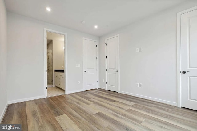 unfurnished bedroom featuring connected bathroom and light hardwood / wood-style flooring